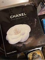 Cover of the CHANEL Collections and Creations book featuring a large white camellia flower on black background.