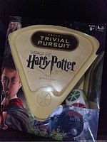 Front view of sealed Harry Potter Trivial Pursuit game inside damaged packaging box showing game logo, dice, and artwork with Harry Potter and Hogwarts Express.