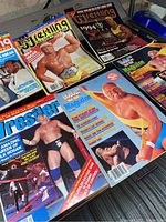 Photo showing five wrestling magazines featuring Hulk Hogan on the cover, displayed on a table surface.