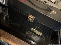 Front view of black textured carrying case with metal clasp and rectangular Nintendo logo plate