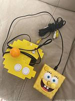 Yellow Pac-Man shaped Plug and Play games console with wired SpongeBob controller featuring two buttons, AV cables included.