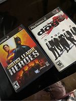 Two PlayStation 2 game cases shown: Justice League Heroes and Reservoir Dogs.