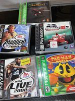Photo of five PlayStation 1 game cases including Madden 2000, NBA Live 2000, Jet Moto 2, Formula 1, and Pac-Man World arranged in a cluster.