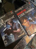 Photo shows two PlayStation 2 game cases of Resident Evil 4 and Resident Evil Code: Veronica with manuals included.