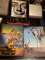 Art print of surrealistic scene with figures on long stilts, a man kneeling and a horse figure with drawers, typical of Dali's style.