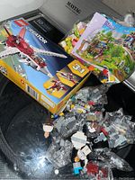 Photo of Lego Creator 3-in-1 airplane box and various small bags of Lego pieces, including minifigure parts and bricks.