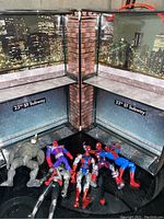 Open carrying case with cityscape and subway background, 7 action figures displayed inside including Spider-Man figures and grey villain figure