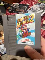Close-up photo of the Super Mario Bros 2 NES game cartridge held in hand.