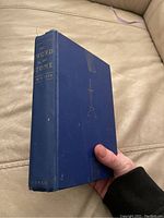 Front angled view showing thickness, blue cover with gold embossed sword graphic and title text on spine.