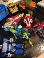 Photo showing seven Transformers toys in various forms including vehicles and robots on a black surface.