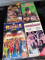 Photo showing four WWF wrestling VHS tapes with colorful covers including Royal Rumble 1991 and 1994, Sgt. Slaughter, and Summerslam 89.