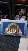 Photo of the boxed 12 piece nativity scene with stable and figurines displayed on packaging.