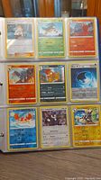 Photo of 9 assorted Pokémon cards in a binder sleeve, showing various character and energy cards.