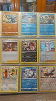 Photo displaying 9 individual Pokemon cards arranged in a 3x3 layout on table.
