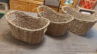 Photo showing three natural wicker baskets placed side by side on a wooden surface, highlighting their size and shape.