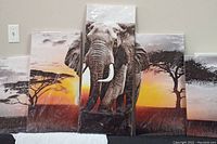 Five separate canvas panels arranged horizontally on a wall, featuring a large elephant in the center against a savannah sunset background with trees.