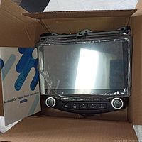 Photo of Android car media player unit inside a cardboard box with instruction manual