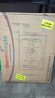 Cardboard box showing Thermamate logo, burner layout graphic and caution labels