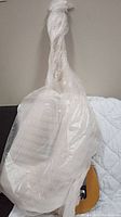 Electric guitar fully wrapped in protective plastic film and bubble wrap showing body outline and neck heel.