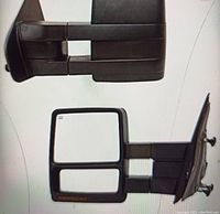Two black towing mirrors side by side showing front and rear views, rectangular dual mirror with turn signal and puddle lamp indicator light areas