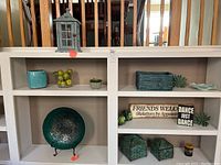 Wide view of shelves showing various decorative items including baskets, plates, vases, signs, and artificial fruit.