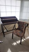 Wood desk and upholstered side chair side by side in a room.
