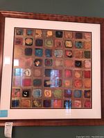 Framed abstract art with colorful squares in grid pattern, wood-finish frame and white matting.