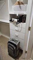 Overall view of suitcase at bottom, hats in basket on shelf and purses displayed on shelf