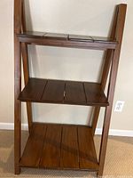 Front view of the wooden three-tier shelf showing the graduated shelf sizes and wood plank design.
