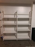Front view showing two columns of shelving with five shelves each, white metal frame and white MDF shelves.