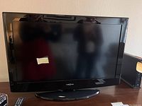 Insignia flat-screen TV on a wooden surface with remote control visible.