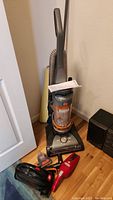 Hoover upright vacuum with hose and manual, Dirt Devil handheld vacuums placed on floor around it.