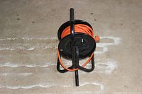 View from above showing the orange extension cord wound on black metal reel in a horizontal position.