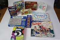 Large group of assorted board games, including Twister, Crack the Case, Bottle Tops, Sequence for Kids, The Talking Jigsaw Puzzle, and others all arranged on floor.