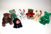 Seven vintage Teddy Bear Beanie Babies arranged in a row, showing tags and distinctive designs.