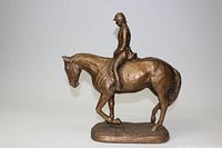 Side profile view of bronze equestrian sculpture showing detailed horse and rider on base.