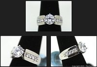 Clear front, side and angled views of the sterling silver engagement ring showcasing the wide band, solitaire round cut simulant diamond and side stones, all on black stand.