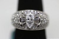 Front view of sterling silver ring with marquise cut simulant diamond center and pave set smaller round stones.