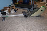 Side view of full rowing machine on carpeted floor.