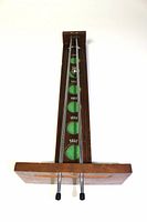 Top-down view showing the full length of the wooden game board with scoring zones and metal launch rods with a metal ball present on the track.