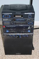 Front view of the VocoPro karaoke system showing DVD, CD, cassette deck, AM/FM radio, controls and speaker.