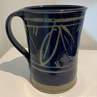 Photo of the front and side of the blue glazed pottery jug with handle and abstract pattern.