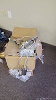 Overall photo of 3-light chrome hanging fixture with cables and sockets on carpeted floor next to damaged cardboard box showing approximate size and packaging.