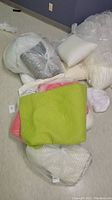 Various bedspreads in different colors and packaging laid on floor