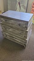 Gray whitewashed dresser with three drawers shown from top angle, displaying finishing and drawer design