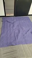 Dark blue moving blanket spread out to show size and quilted pattern.