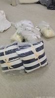 Blue and white striped pillows wrapped in plastic bags tied with beige ribbons, resting on floor.