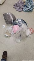 Photo showing three throw blankets and one dark brown bedspread on carpeted floor, all wrapped in plastic bags.