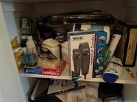 Overview showing Wahl HomeCut Combo haircutting kit box in front, Colgate toothpaste 3-pack on the left, Lysol spray behind, and assorted bathroom and household items such as lotion bottles and foil furniture protection sheets scattered around.