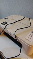 White Canon multifunction printer with cable on top, showing overall shape and condition
